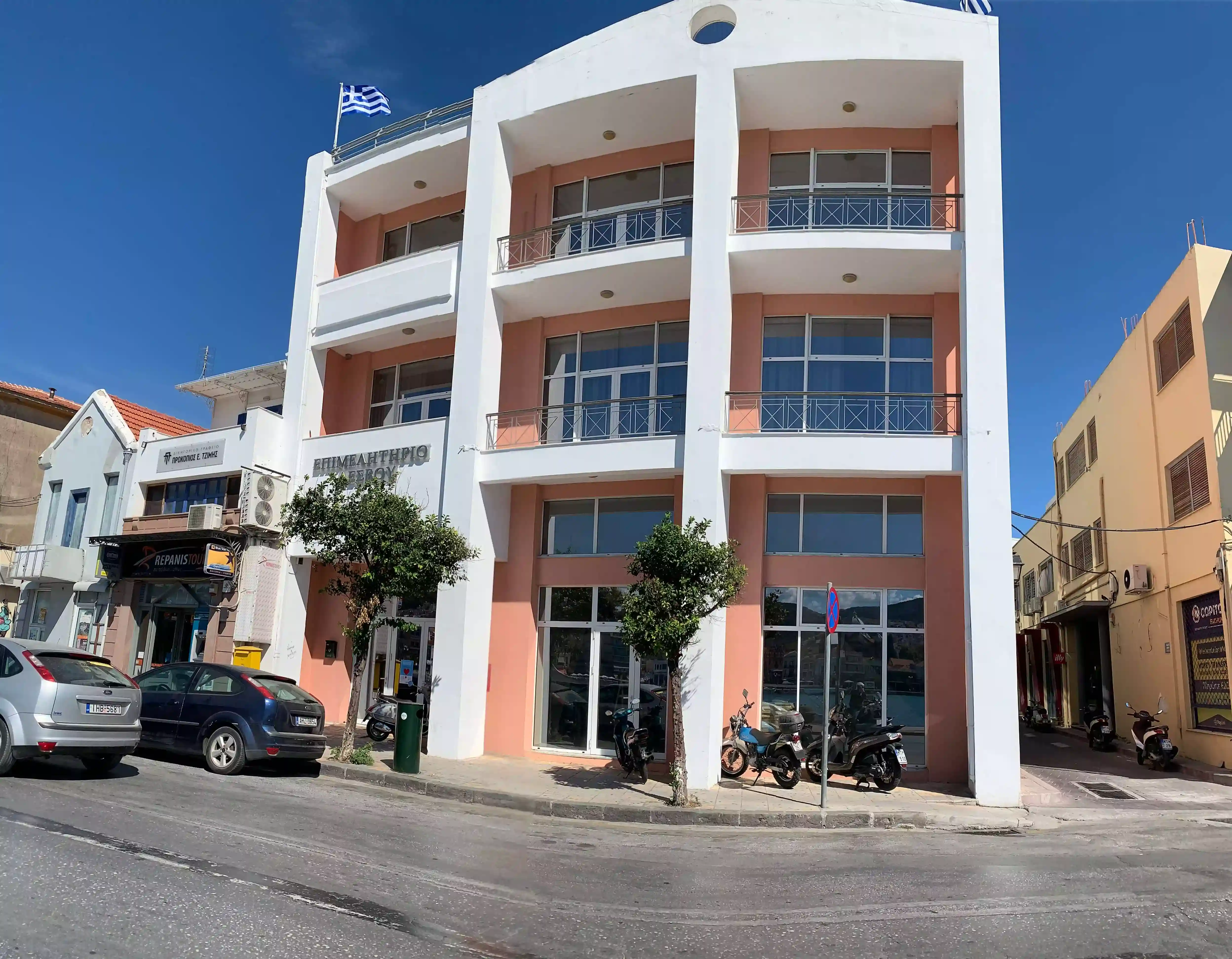 Πρόσοψη του κτηρίου Επιμελητηρίου Λέσβου κατα τη διάρκεια της ημέρας. Το κτήριο έχει κολώνες και μπαλκόνια άσπρου χρώματος, ενώ το υπόλοιπο είναι χρώμα πορτοκαλί.